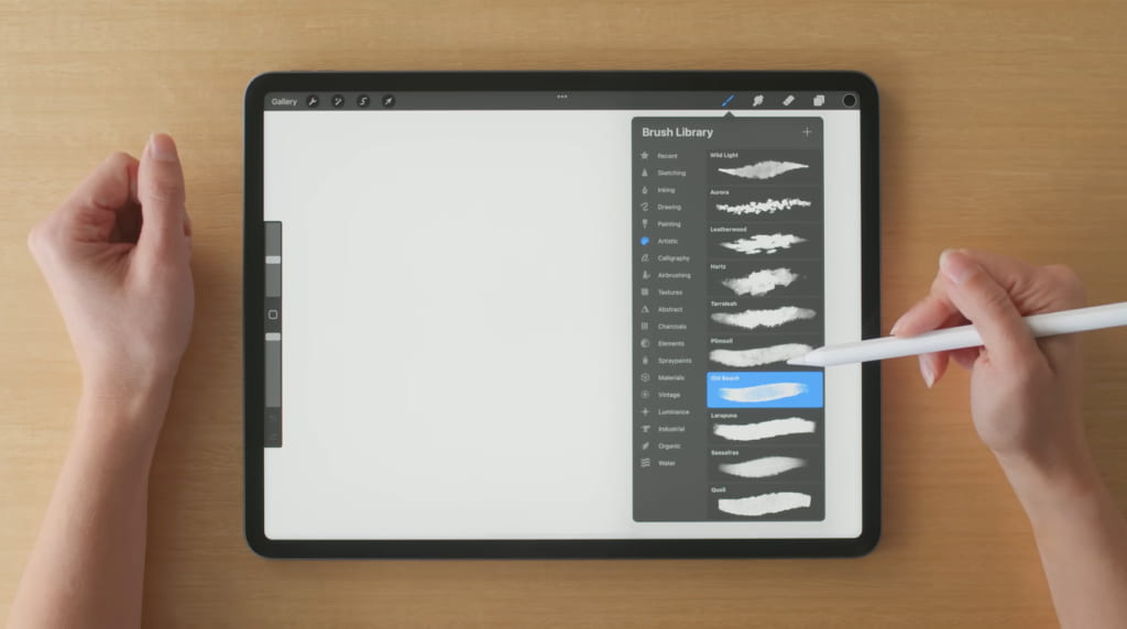 hands holding a stylus above a digital tablet displaying a brush selection menu with "Old Beach"