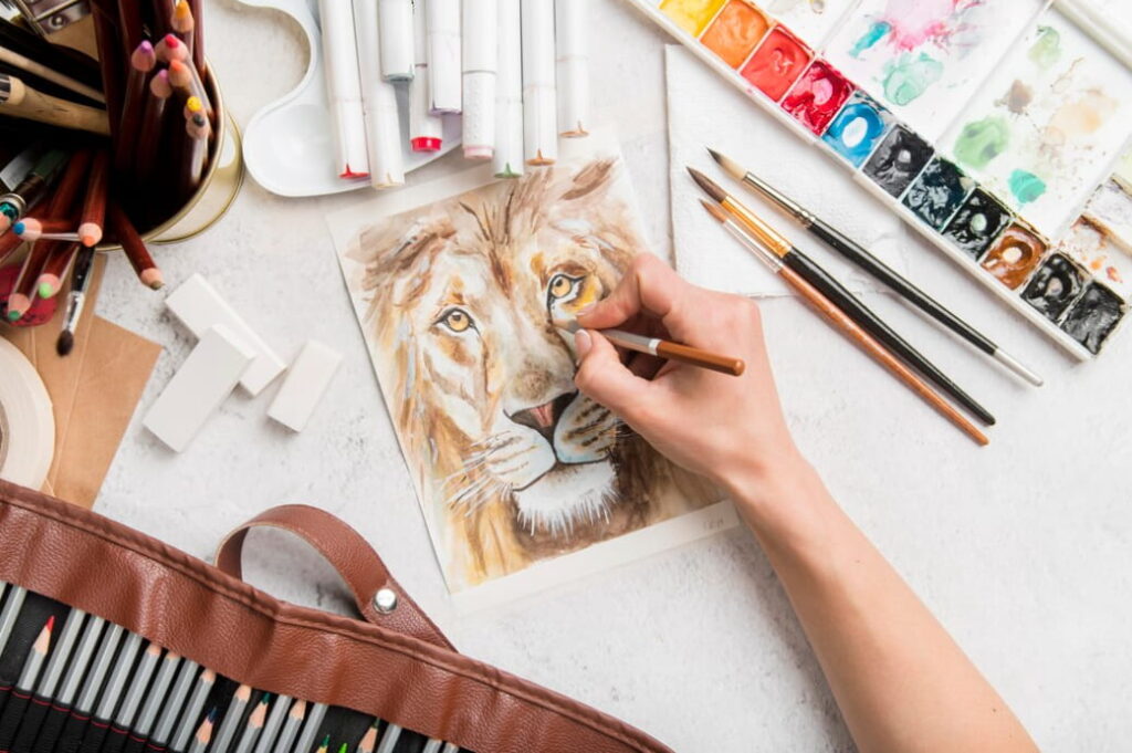 hand drawing a lion, the brushes, paints on a white table